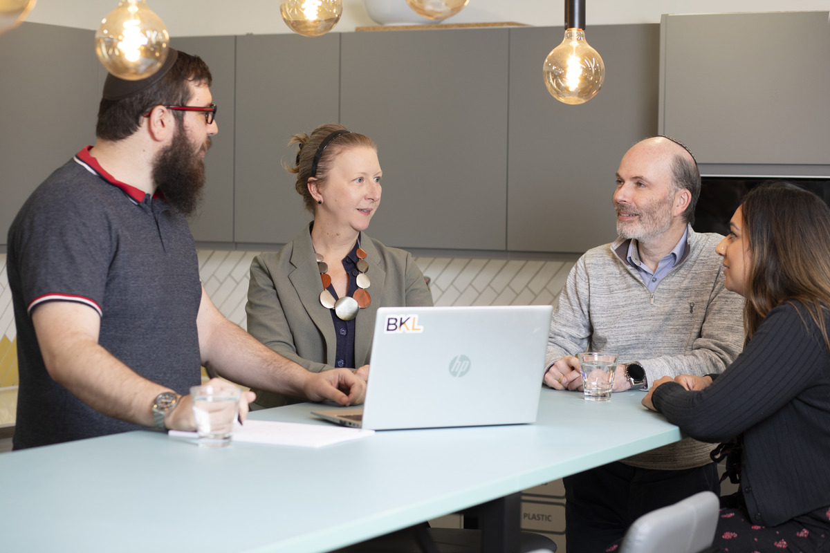 four people gathered round a laptop